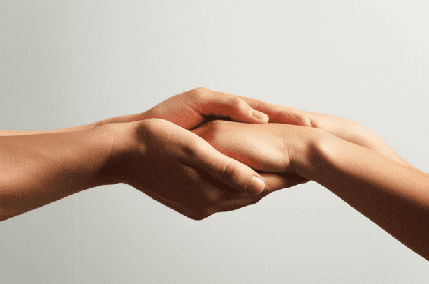 alt_text: Close-up of two hands gently clasped, symbolizing empathy, understanding, and support. Warm, serene light.